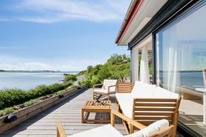 a balcony with a table and chairs and a view of the water at Lovely Beach House With Panoramic View in Martofte +16 photos