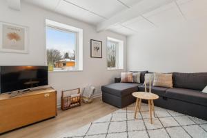 a living room with a couch and a tv at Cosy House Near Forest in Rønne