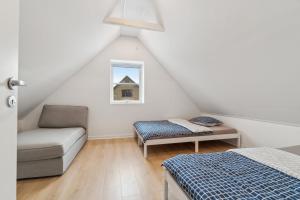 a attic room with a bed and a couch at Cosy House Near Forest in Rønne
