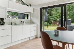 a kitchen with white cabinets and a table and chairs at Scenic Summer House In Asserbo in Frederiksværk +23 photos
