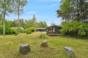 a house in a field with rocks in the yard at Scenic Summer House In Asserbo in Frederiksværk
