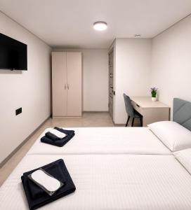a room with two beds and a desk and a television at EVURI Rooms in Uzhhorod