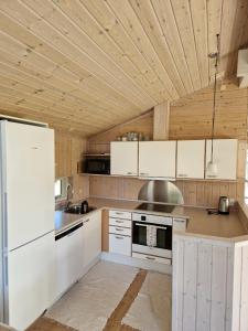 a kitchen with white appliances and a wooden ceiling at Cozy And Well-Maintained Holiday Home in Eskebjerg