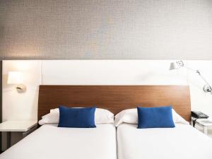 two beds in a hotel room with blue pillows at Ibis Styles A Coruna in A Coruña