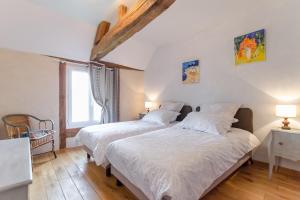 two beds in a room with white walls and wooden floors at Le clos des berdins in Saint-Jean-de-Bonneval