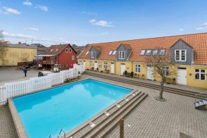 a large swimming pool in a courtyard with houses at Holiday Apartment With Pool On Bornholm in Gudhjem
