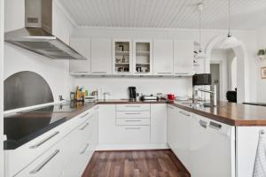 a white kitchen with white cabinets and a wooden floor at Summer House In Thyholm in Thyholm +13 photos