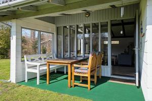 a porch with a wooden table and chairs on it at Cozy Cottage Near Bjerge Strand in Store Fuglede
