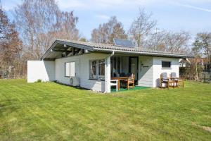 a small white house with a table and chairs at Cozy Cottage Near Bjerge Strand in Store Fuglede