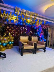 a happy new year party with balloons and two chairs at Hotel The Novelty in Kānpur