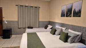 a hotel room with two beds with green pillows at Suítes privativas, camas confortáveis, piscina, churrasqueira e playground, Roupa de Cama e tolha de banho. in Rubinéia +26 photos