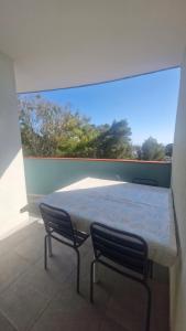 a bed and two chairs in a room with a window at Grand T3 face au port avec sa terrasse , parking privatif in Saint-Cyprien-Plage