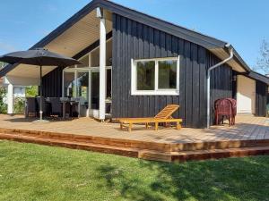 a house with a deck with a bench and an umbrella at Holiday Home Near Hvalpsund in Farsø