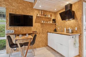 a kitchen with a small table and a tv on a wall at Small Oasis Near Coast And Town in Ebeltoft +17 photos