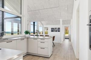 a kitchen with white cabinets and a large window at Seaside Cottage With A Stunning View in Allingåbro +29 photos