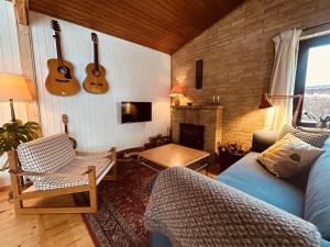 a living room with a couch and guitars on the wall at Charming And Cozy Cottage in Tranekær