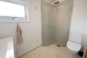 a white bathroom with a shower and a toilet at The Pearl In Marielyst in Bøtø By