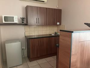a kitchen with wooden cabinets and a microwave at Andante Guesthouse Klerksdorp in Klerksdorp