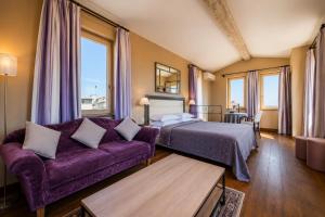 a bedroom with a purple bed and a purple couch at Hôtel Amphithéâtre in Arles
