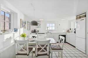 a white kitchen with a white table and chairs at Family-Friendly Beachside Holiday Home in Rønne