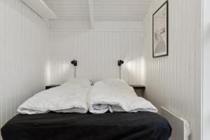 a bed with white sheets and pillows in a room at Cozy Holiday Home On Orø in Orø