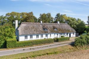 an old house with a thatched roof on a road at Idyllic Half-Timbered House For 10 Guests in Kettinge