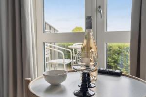 a wine bottle and a bowl on a table with a window at Pension Koch Apartment 6 in Gudhjem