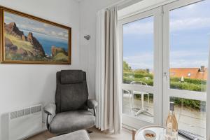 a living room with a chair and a window at Pension Koch Apartment 6 in Gudhjem +4 photos