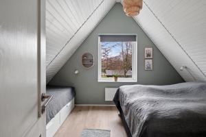 a attic bedroom with a bed and a window at Holiday Home With Spa Sauna And Hot Tub in Farsø