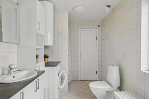 a white bathroom with a toilet and a sink at Holiday Home With Spa Sauna And Hot Tub in Farsø +17 photos