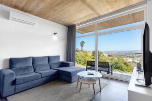 a living room with a blue couch and a large window at Colina do Sol 2 in Amoreira