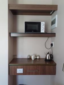 a microwave sitting on a shelf in a kitchen at Andante Guesthouse Klerksdorp in Klerksdorp