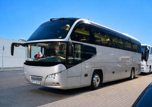 a large white bus parked in a parking lot at Bazarstore Montin Hotel in Baku
