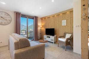 a living room with a couch and a tv and a clock at Maison "Casabert" in Saint-Martin-de-la-Porte