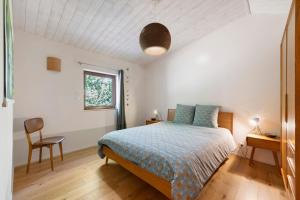 a bedroom with a bed and a chair and a window at Gite Le Koto in Thorigny