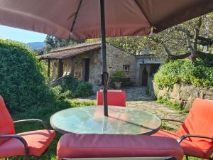 a glass table and chairs under an umbrella at El Valle in Piedralaves