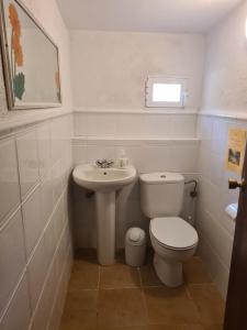 a white bathroom with a toilet and a sink at El Valle in Piedralaves