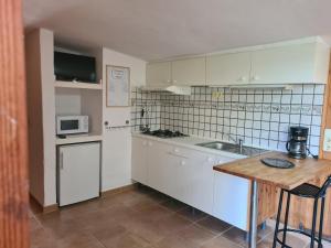 a kitchen with white cabinets and a wooden table at El Valle in Piedralaves +5 photos