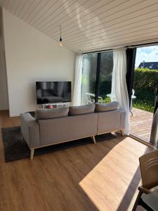 a living room with a couch and a flat screen tv at Stylish Cottage Near Beach Cliffs Harbour in Havnelev