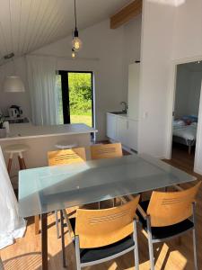 a kitchen and dining room with a glass table and chairs at Stylish Cottage Near Beach Cliffs Harbour in Havnelev