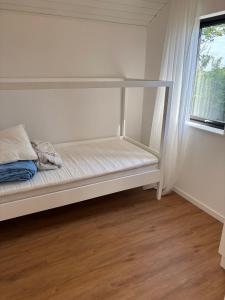 a white bed in a room with a window at Stylish Cottage Near Beach Cliffs Harbour in Havnelev