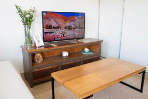 a living room with a tv and a wooden table at Delta Boutique Loft, en el centro de Salta, para 3 by BEDBOOK in Salta