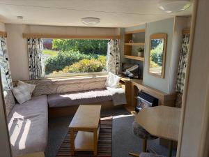 a living room with a couch and a window at Northfield Holiday Park in Borth