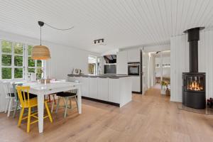 a kitchen and dining room with a table and a stove at Renovated Classic Cottage Close To Beach in Roslev