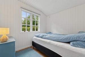 a bedroom with a bed and a window at Renovated Classic Cottage Close To Beach in Roslev