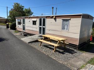 a wooden picnic table next to a trailer at Northfield Holiday Park in Borth