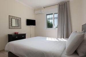 a bedroom with a white bed and a window at Villa Renata -Pool, Large Garden & Free Parking, 2 Minutes Walk from The Beach in Barbati