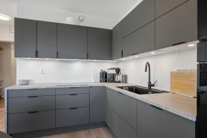 a kitchen with black and white cabinets and a sink at Penthouse with Rooftop Terrace & Balcony in Bergen