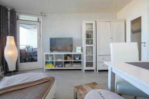a living room with a tv on a white cabinet at Strandhotel Dahme TraumMeerBlick in Dahme