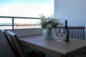 a wooden table with two wine glasses and a vase with flowers at Strandhotel Dahme TraumMeerBlick in Dahme